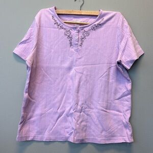 Woman’s lilac colored blouse with floral round neck line button up on neck.